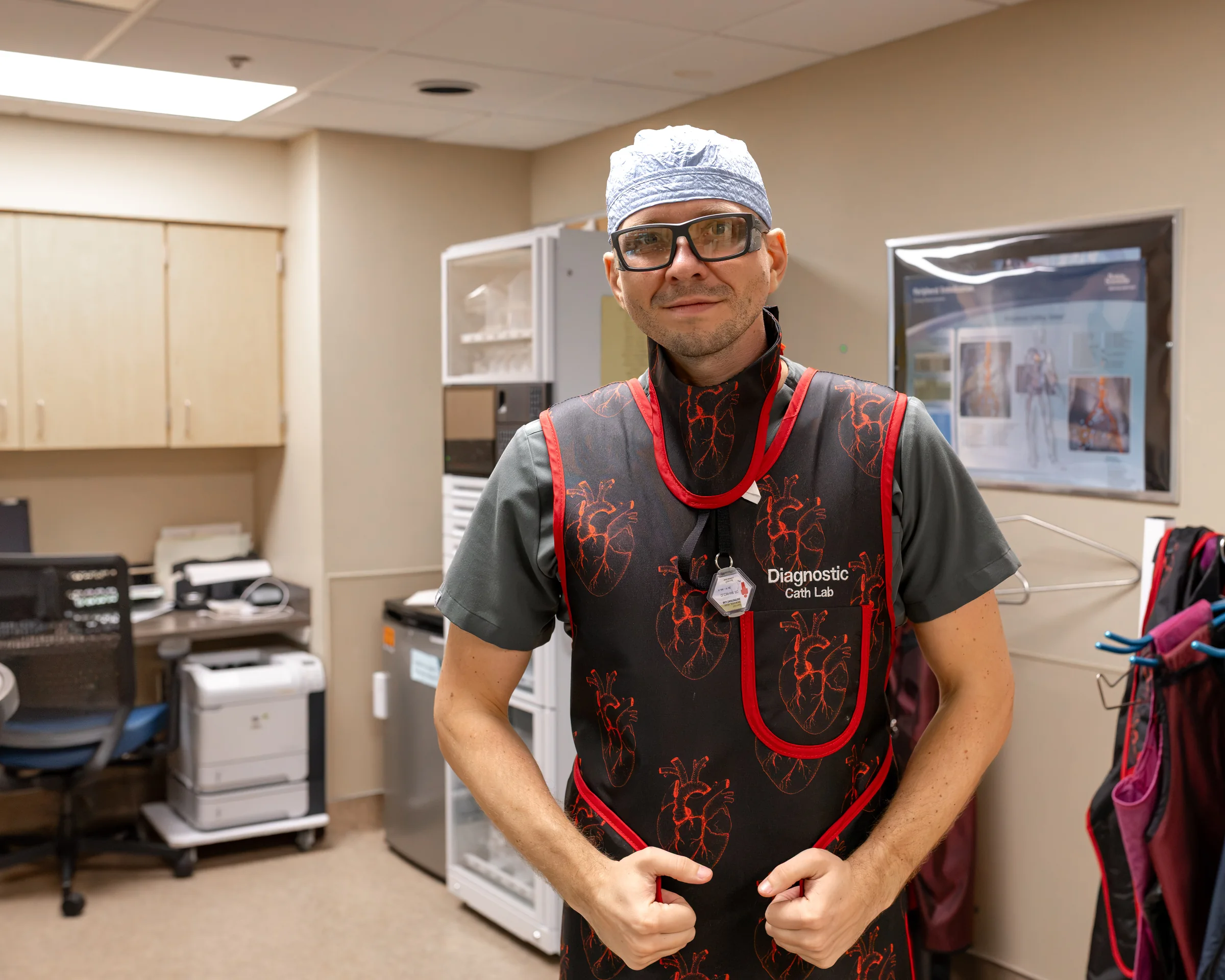 Dr. Yaranov in a surgical cap, protective glasses and a heart-print lead apron marked Diagnostic Cath Lab