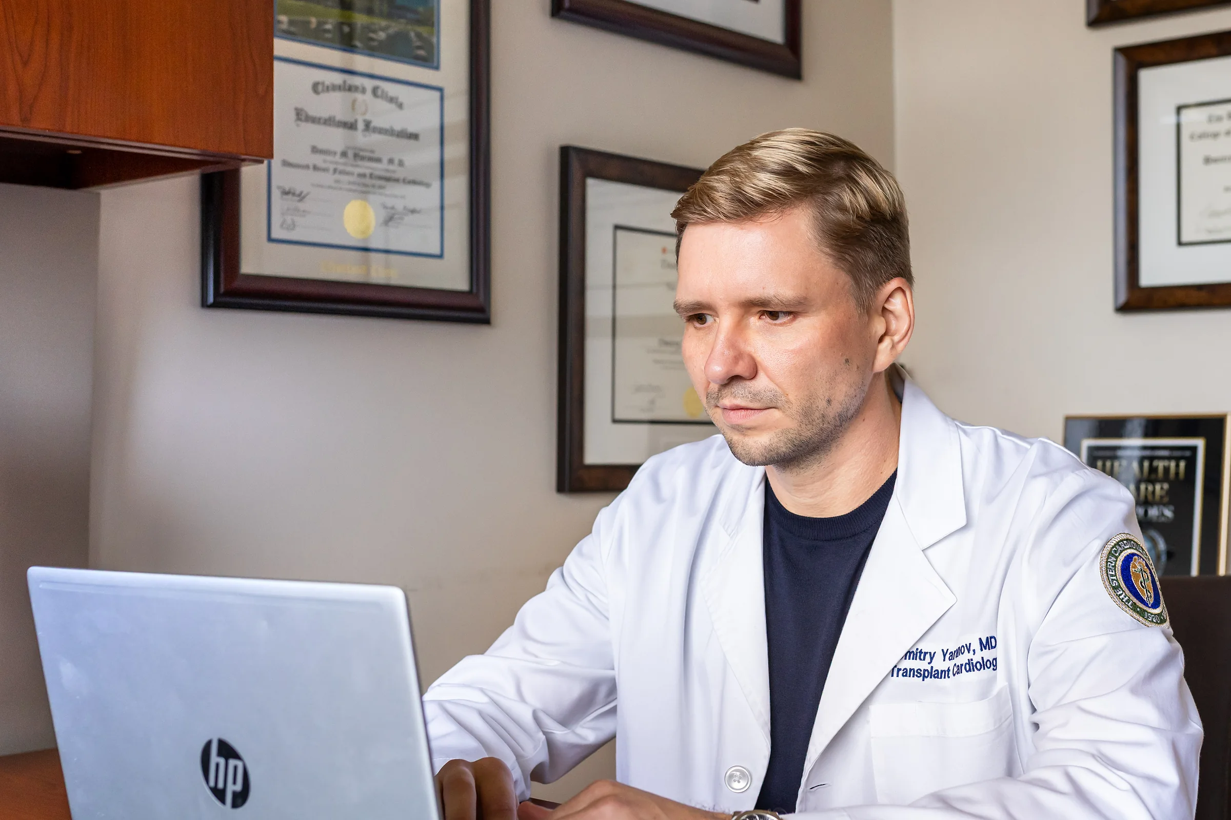 Dr. Yaranov in his white coat, typing at his laptop in his office