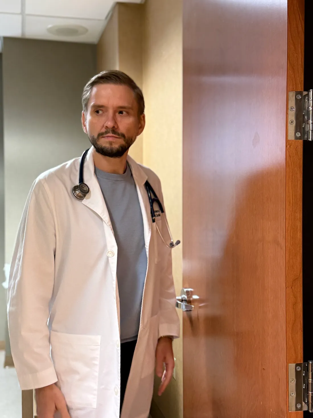 Dr. Yaranov in a white coat with a stethoscope, standing at an exam room door